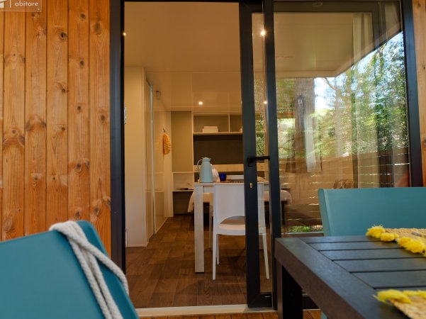 Interno di una casa con tavolo, sedie e accesso a un patio esterno.