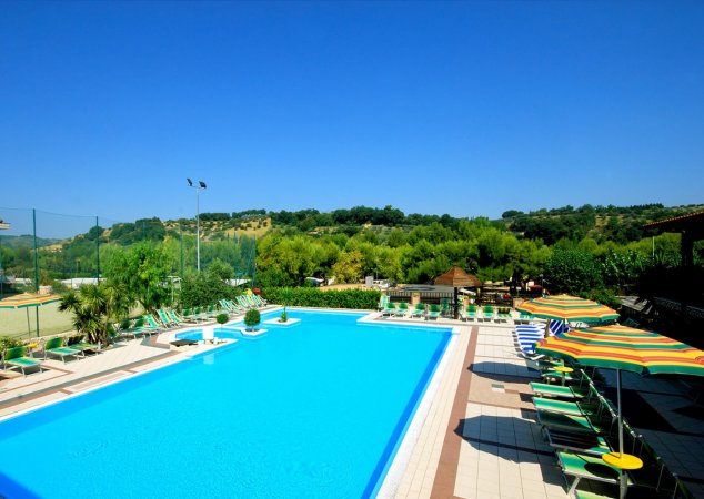 Piscina blu circondata da lettini e ombrelloni.