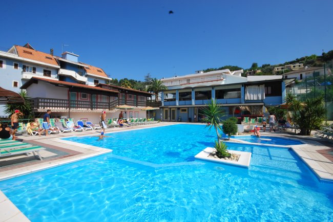 Piscina con lettini colorati e palme intorno.