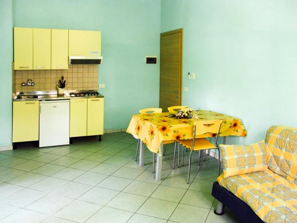 Cucina moderna con tavolo giallo e divano a quadri.