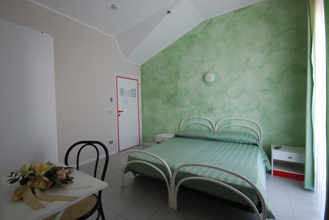 Camera con letto matrimoniale e parete verde.