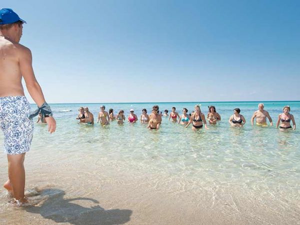 Persone in acqua vicino alla riva su una spiaggia soleggiata.