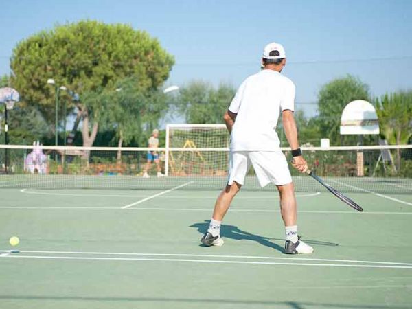 Un uomo gioca a tennis su un campo all'aperto.
