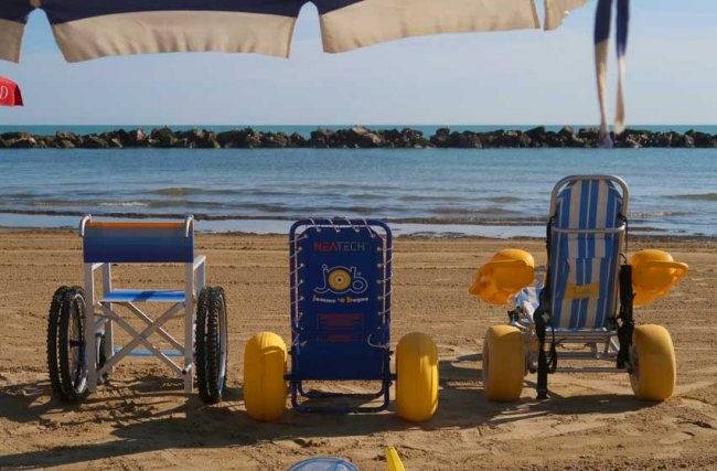 Sedia a rotelle da spiaggia sulla sabbia davanti al mare.