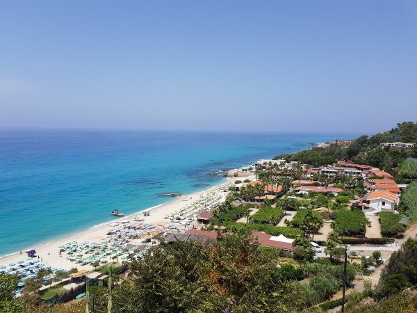 Vista panoramica di una costa con spiaggia e mare azzurro.