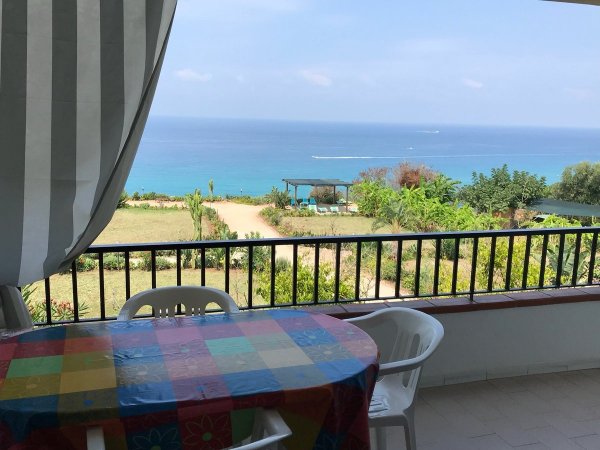 Tavolo con tovaglia a quadri su balcone vista mare.