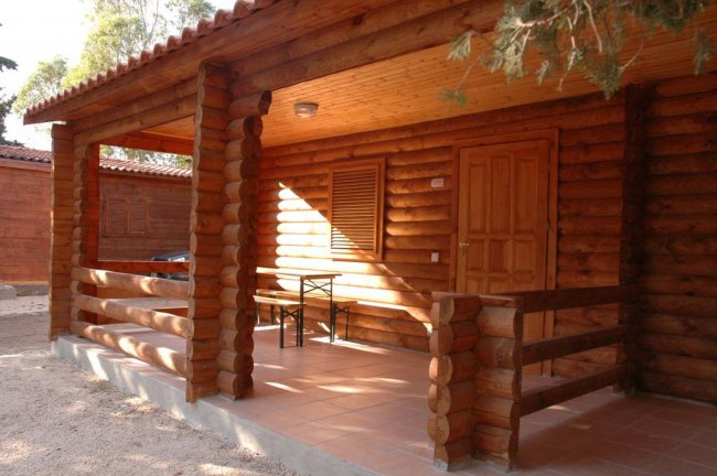Una veranda in legno con due sedie e un tavolo, accanto a una porta di legno.