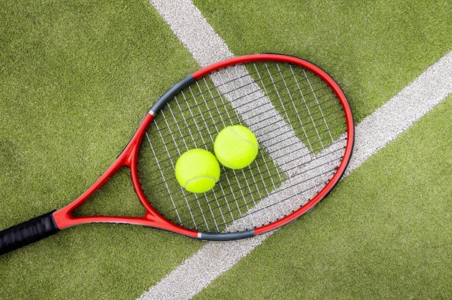 Racchetta e palle da tennis su campo.