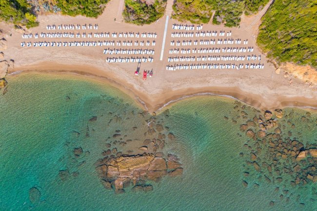 Vista aerea di una spiaggia con lettini e acqua cristallina.