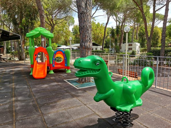Area giochi con dinosauro a molla e scivolo.