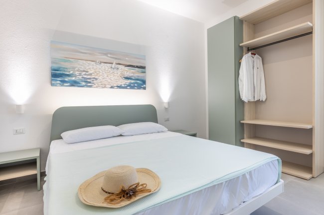 Letto matrimoniale con cappello e camicia appesi vicino.