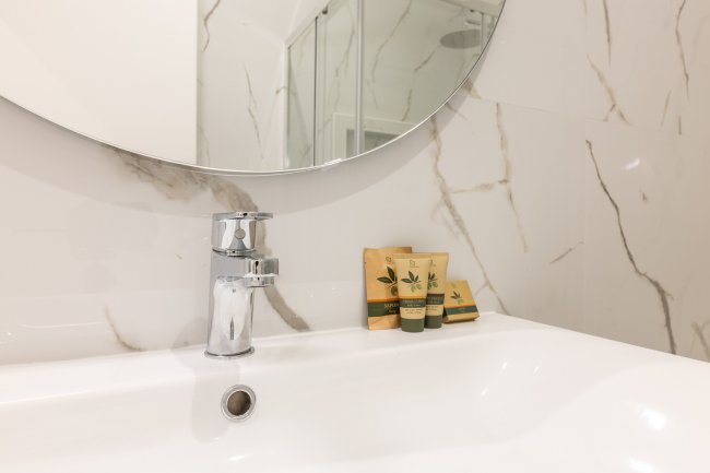 Dettaglio lavabo con specchio e prodotti.