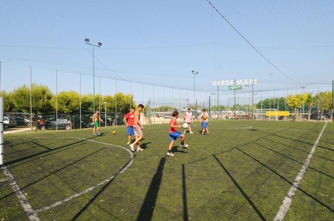 Persone giocano a calcio su un campo all'aperto.