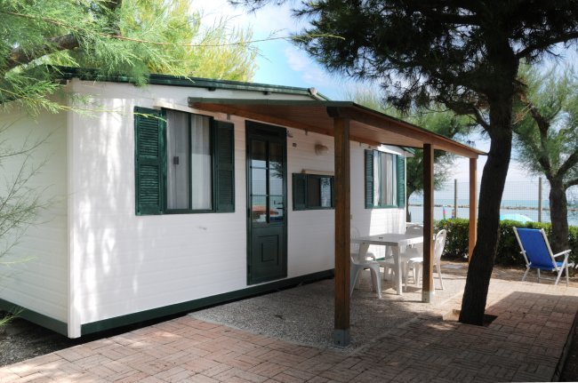 Casa mobile bianca con veranda, tavolo e sedie.