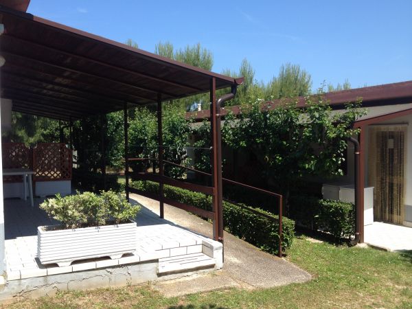 Terrazza coperta accanto a un giardino curato.