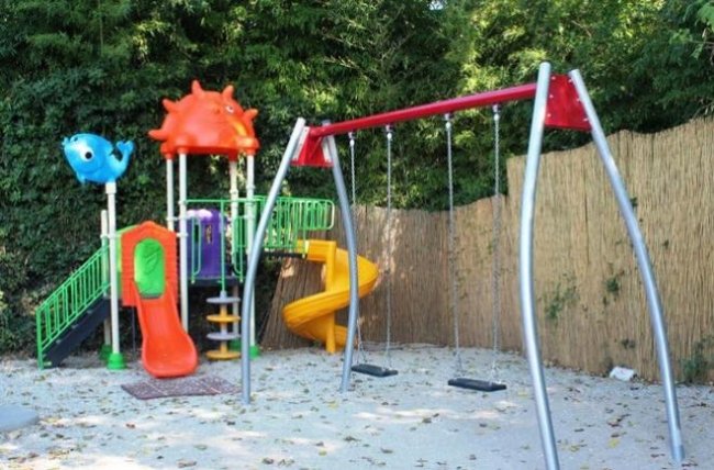 Parco giochi con altalene e scivoli colorati.