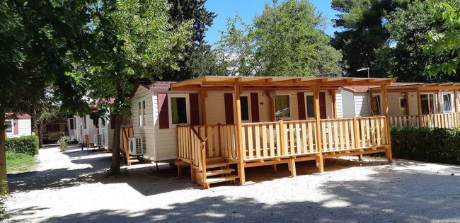 Bungalow con veranda in legno tra gli alberi.