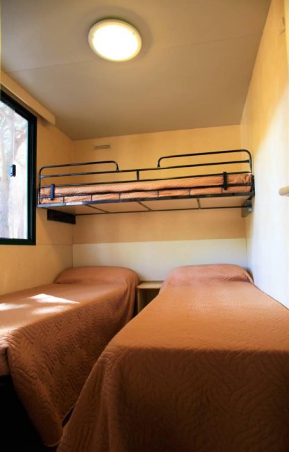 Camera con due letti singoli e un letto a castello, copriletti marroni.