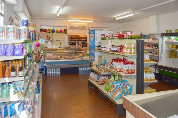 Negozio interno con scaffali pieni di prodotti alimentari e di consumo.