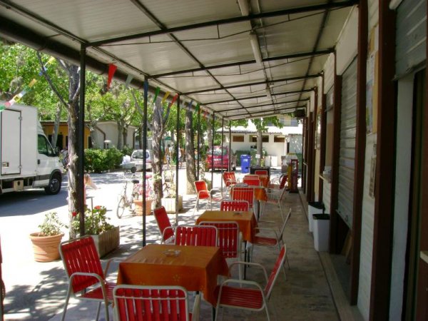 Tavoli e sedie rosse all'esterno di un ristorante coperto.