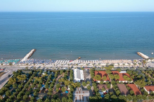 Vista aerea della spiaggia con ombrelloni e mare.