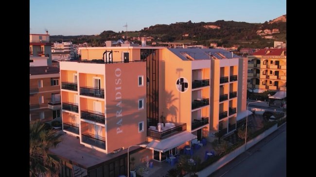 Edificio residenziale arancione con balconi, a fianco di altre strutture.