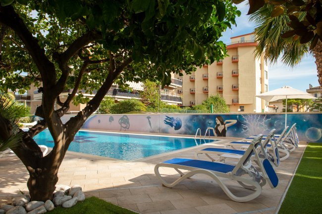 Lettini bianchi e blu accanto a una piscina con murale colorato.