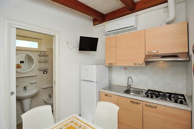 Cucina compatta con bagno visibile a sinistra.