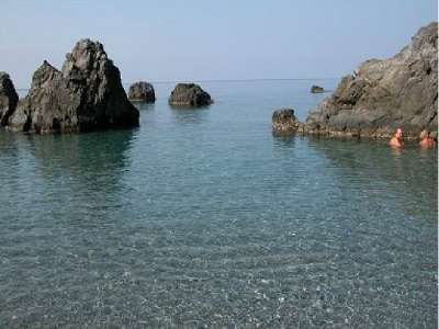 Scogliere immerse in acqua cristallina con alcune persone che nuotano.