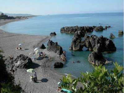 Spiaggia con rocce e ombrelloni, mare calmo.