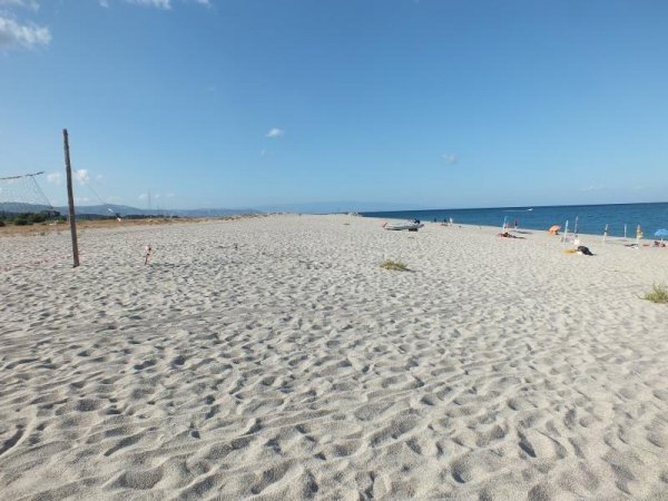 Spiaggia sabbiosa con mare azzurro e cielo sereno.