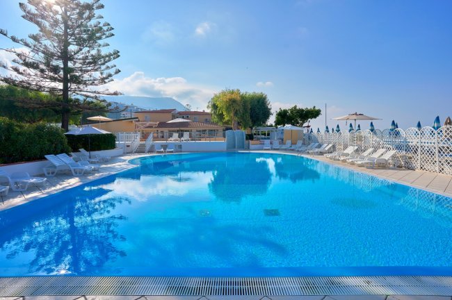 Piscina azzurra con lettini sotto sole.
