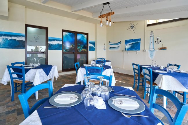 Ristorante con sedie blu e tavoli apparecchiati.
