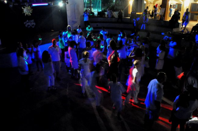 Folla che balla in discoteca con luci colorate.