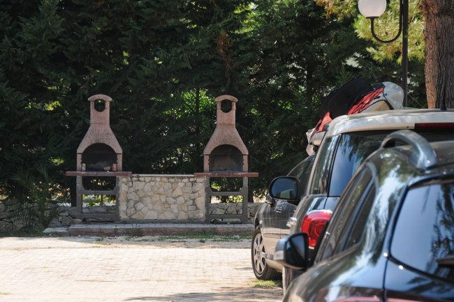 Due barbecue in mattoni vicino a un'auto parcheggiata.