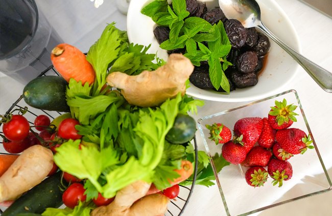 Verdure e frutta, come carote, sedano, fragole e prugne in ciotole.