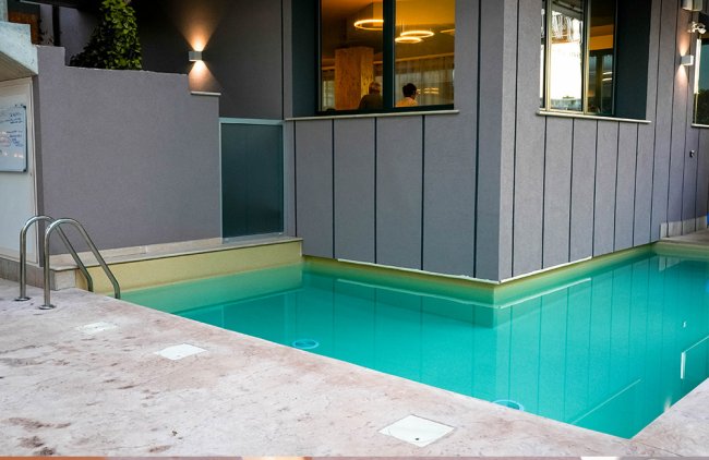 Piscina adiacente a un edificio moderno con finestre.