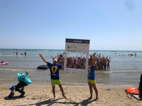 Persone in spiaggia con cornice gigante.