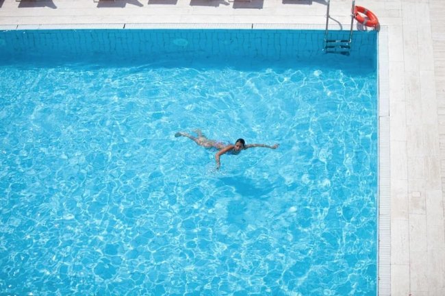 Persona che nuota in una piscina azzurra e limpida.