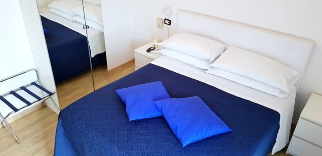 Letto con copriletto blu e cuscini azzurri.