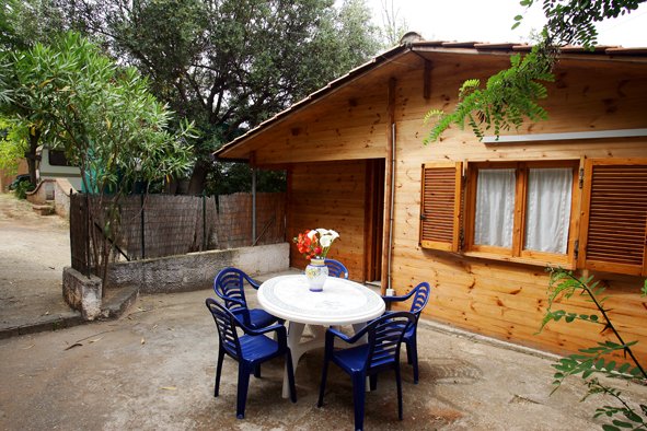Casa in legno, tavolo rotondo con sedie blu all'aperto.