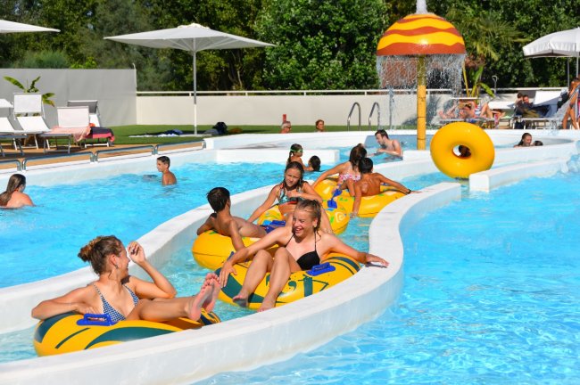 Persone su gommoni in un fiume lento in piscina, sotto il sole.