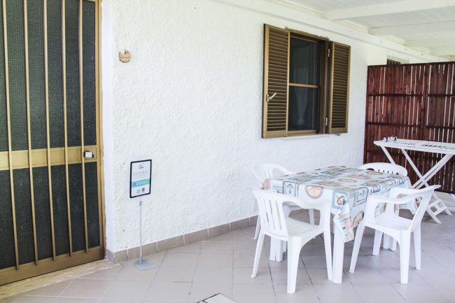 Tavolo e sedie di plastica su terrazza con parete bianca.
