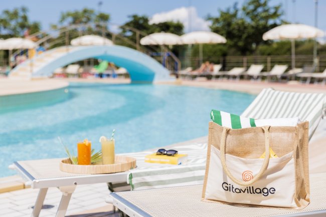 Piscina con sedie a sdraio e un ponte azzurro.
