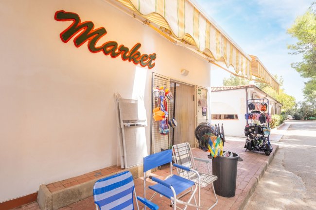 Esterno di un piccolo market con sedie da spiaggia esposte.