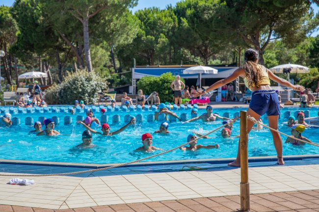 Un gruppo di persone in una piscina seguendo un istruttore.