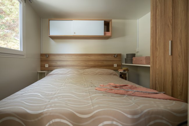 Camera con letto matrimoniale, armadio e mensole.