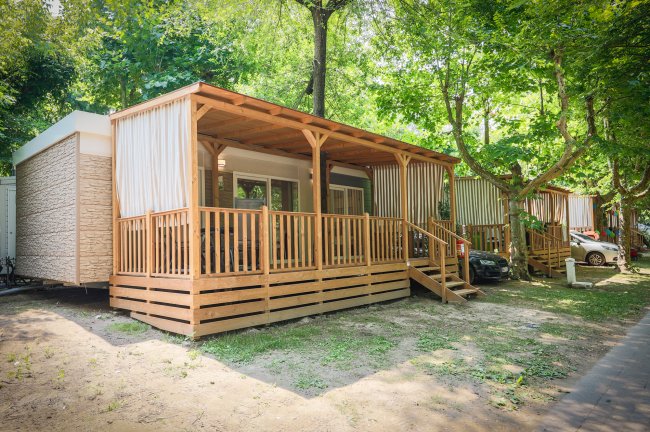 Una moderna casa mobile con veranda in legno immersa nel verde.