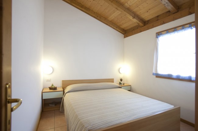 Camera da letto con letto matrimoniale, due comodini e luci accese.