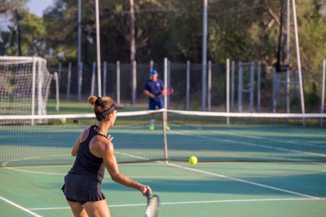 Donna in abbigliamento sportivo gioca a tennis su un campo all'aperto.